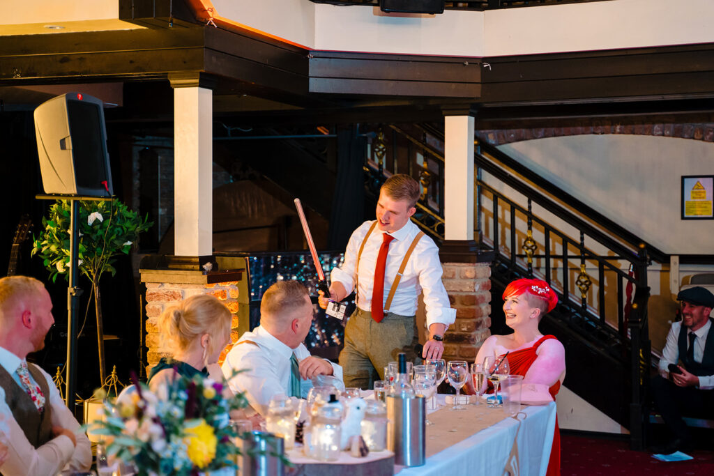 Best man entertaining guests at formal wedding reception dinner
