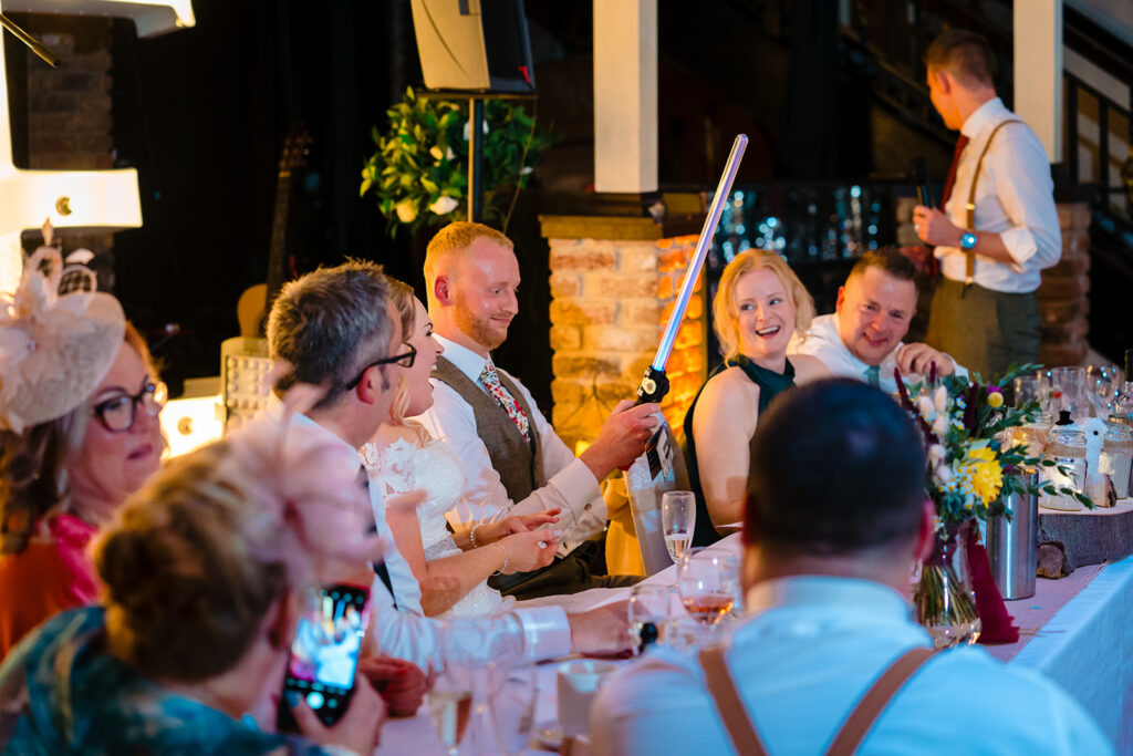 Groom holding lightsaber at evening wedding reception celebration