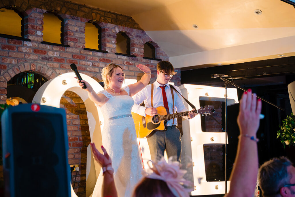 Bride and groom performing with guitar at wedding reception
