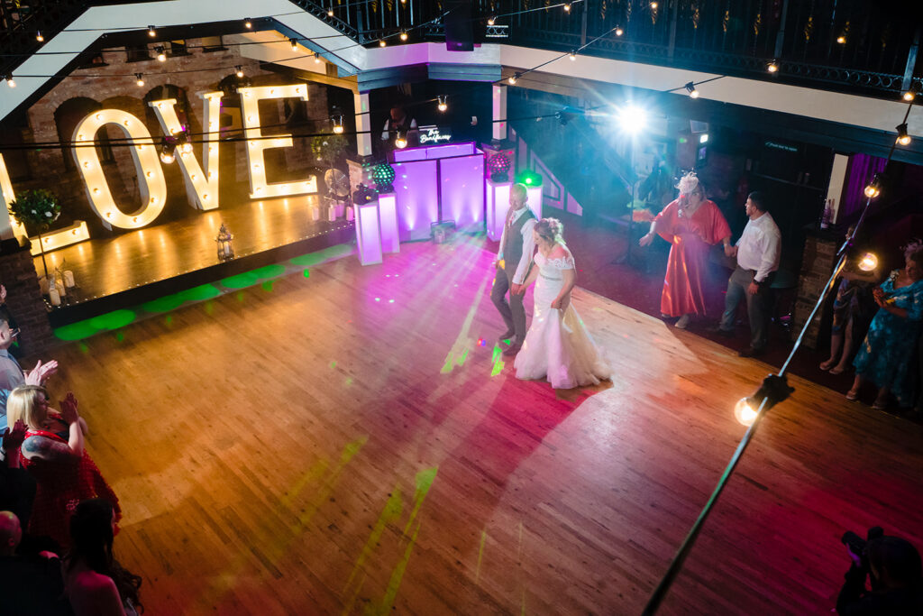 Bride and groom dancing at vibrant wedding reception with LOVE sign