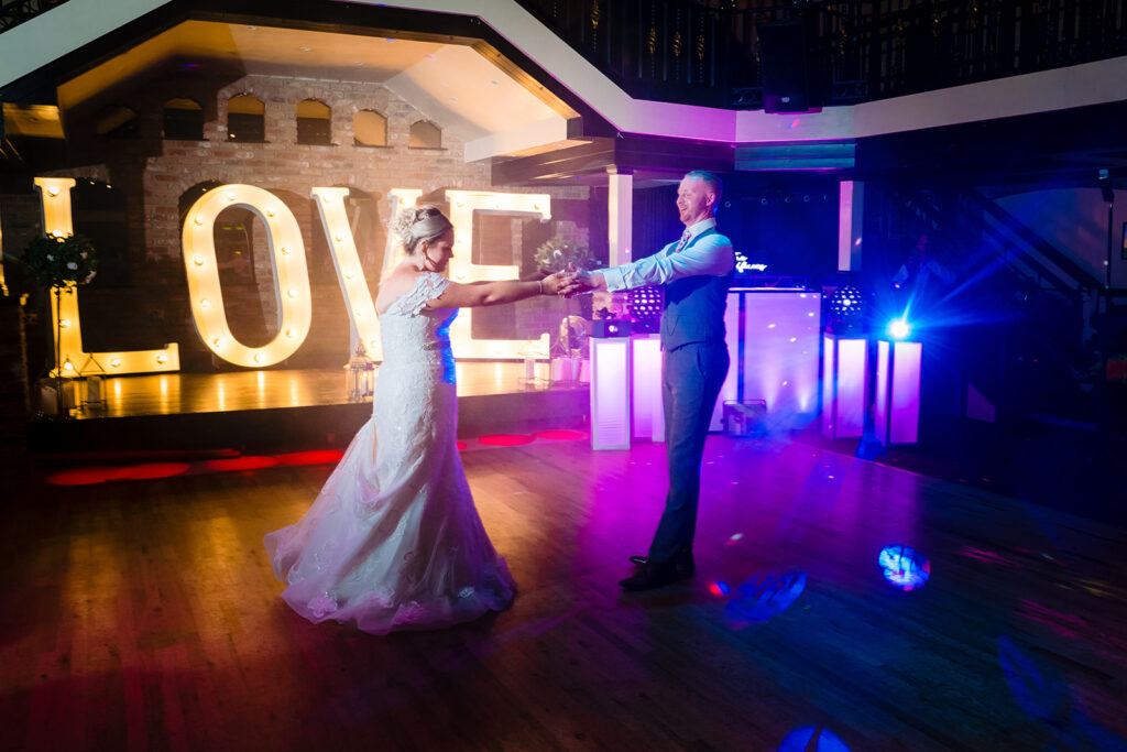 Bride and groom dancing at wedding reception with LOVE sign