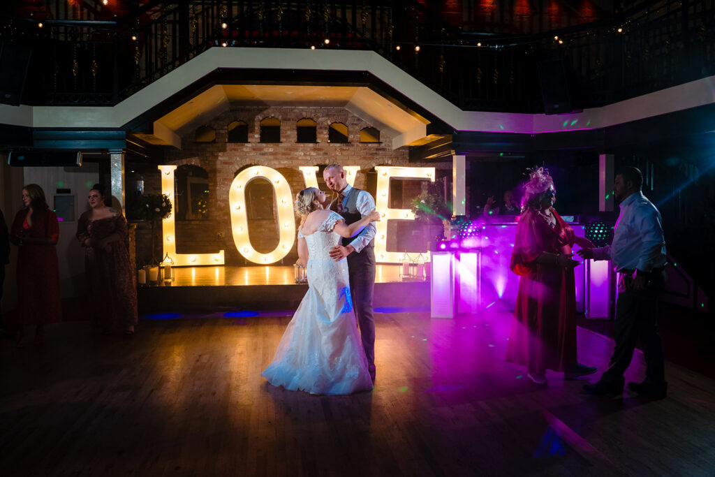 Bride and groom dancing at wedding reception with LOVE sign