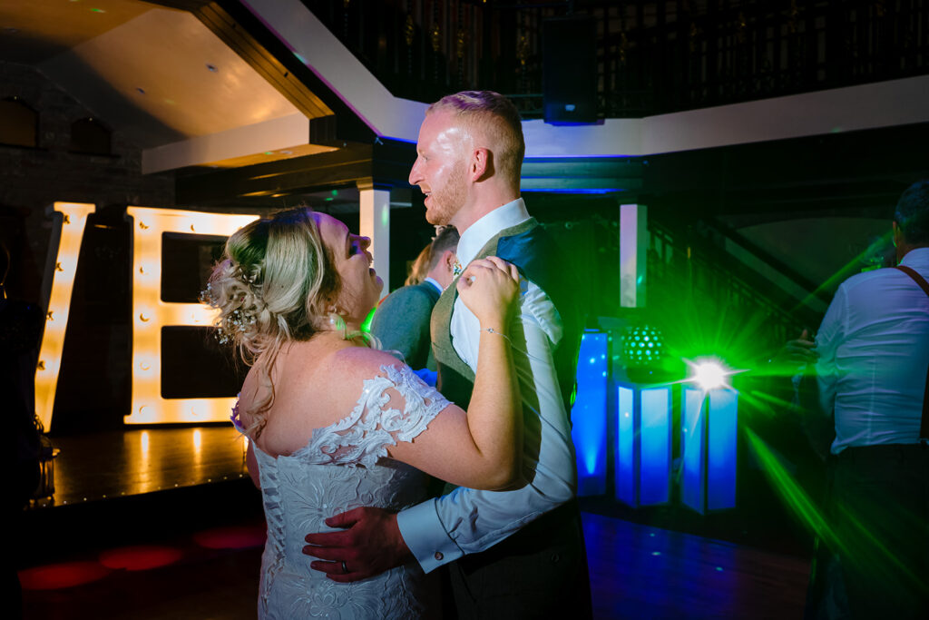 Couple dancing at wedding reception with coloured lighting