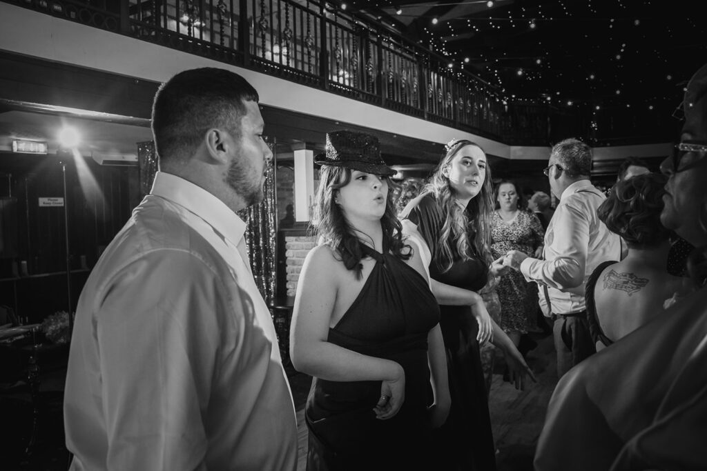 Black and white photo of elegantly dressed people at indoor formal event