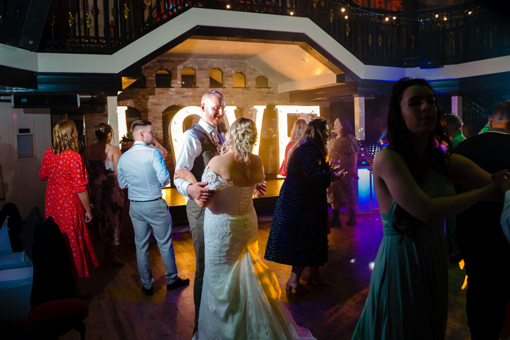 Bride and groom dancing at indoor wedding reception party