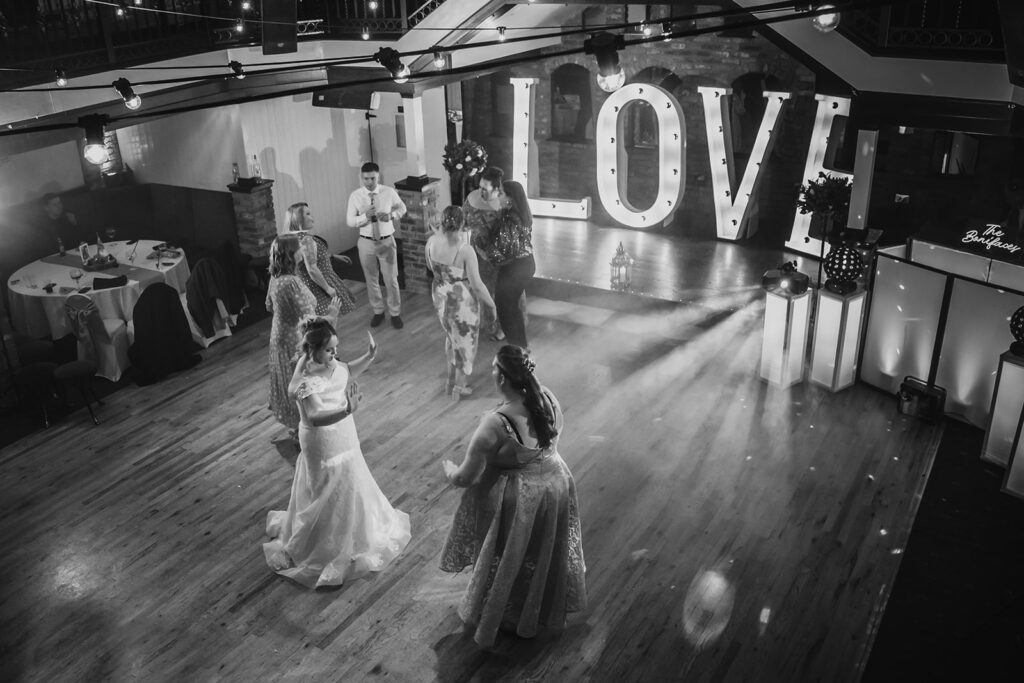Black and white wedding reception with LOVE sign and dancing guests