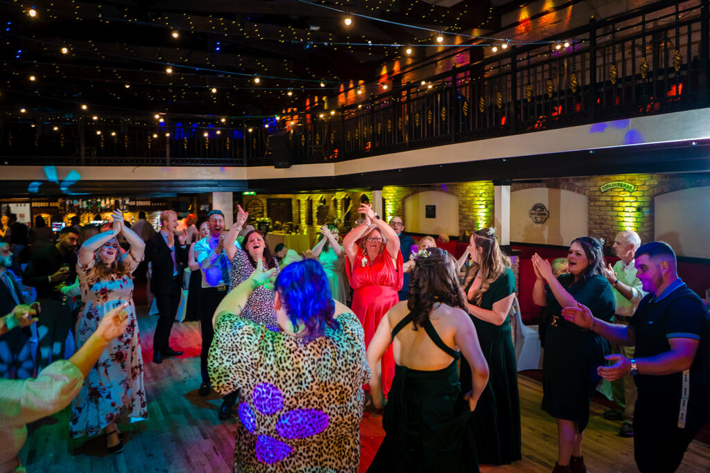 Lively indoor event with guests dancing under colourful lights