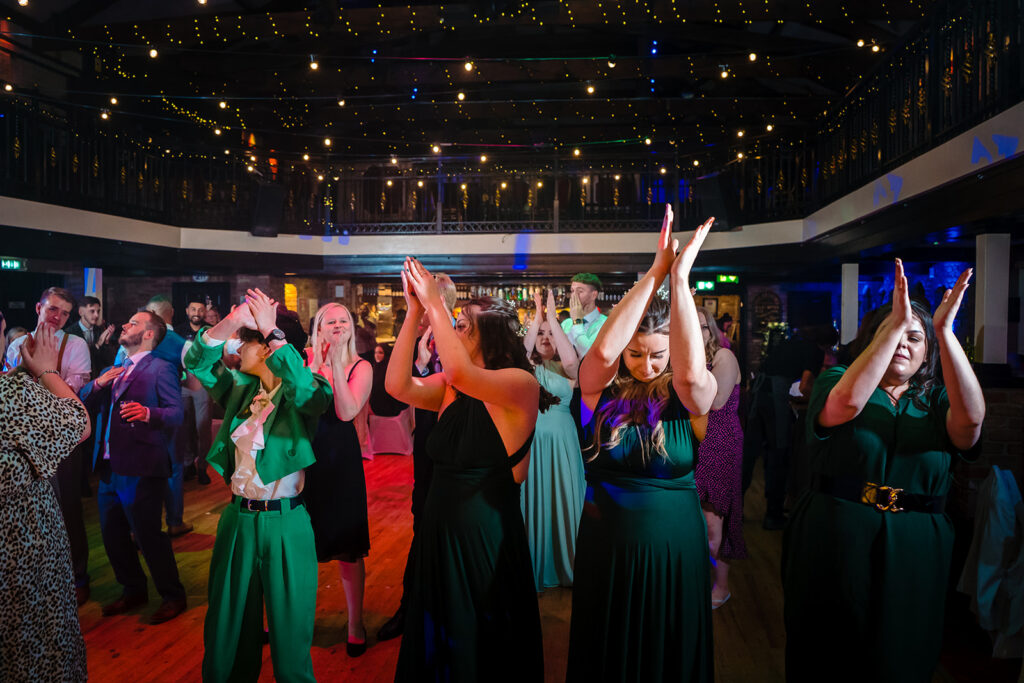 Guests dancing at elegant venue with festive lighting overhead