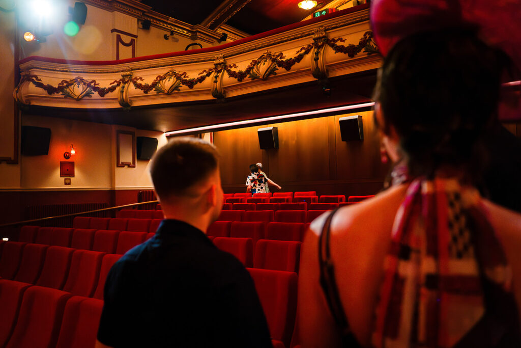 Guests seated in the red velvet seats of the Hyde Park Picture House, with its ornate gold balcony above