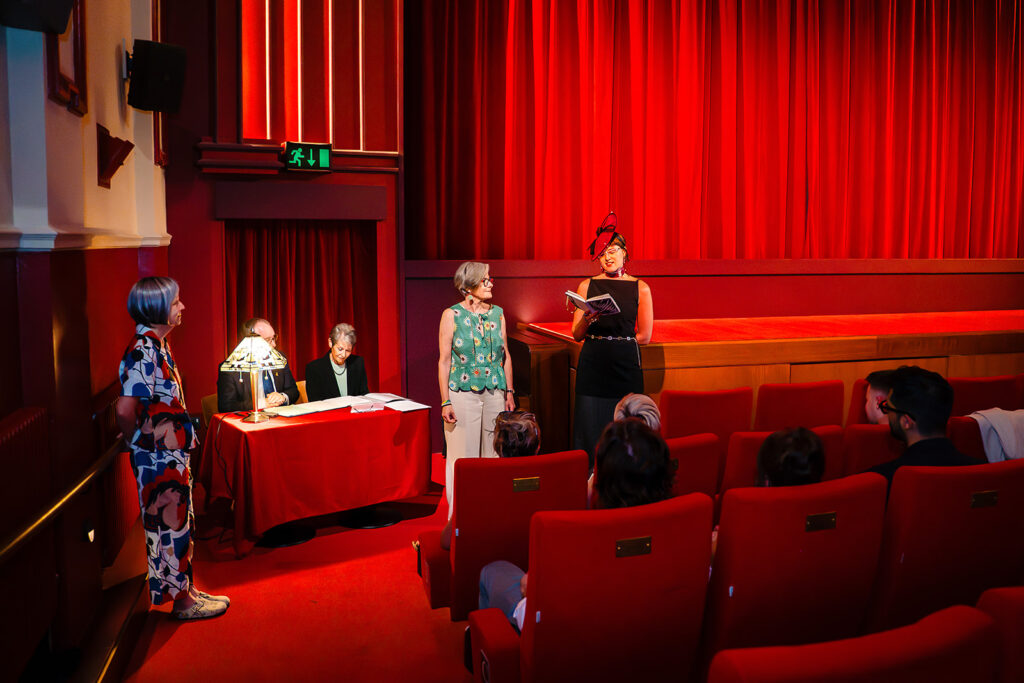 Beverly and Jane at the front of the Hyde Park Picture House auditorium during their ceremony, with the red curtains behind