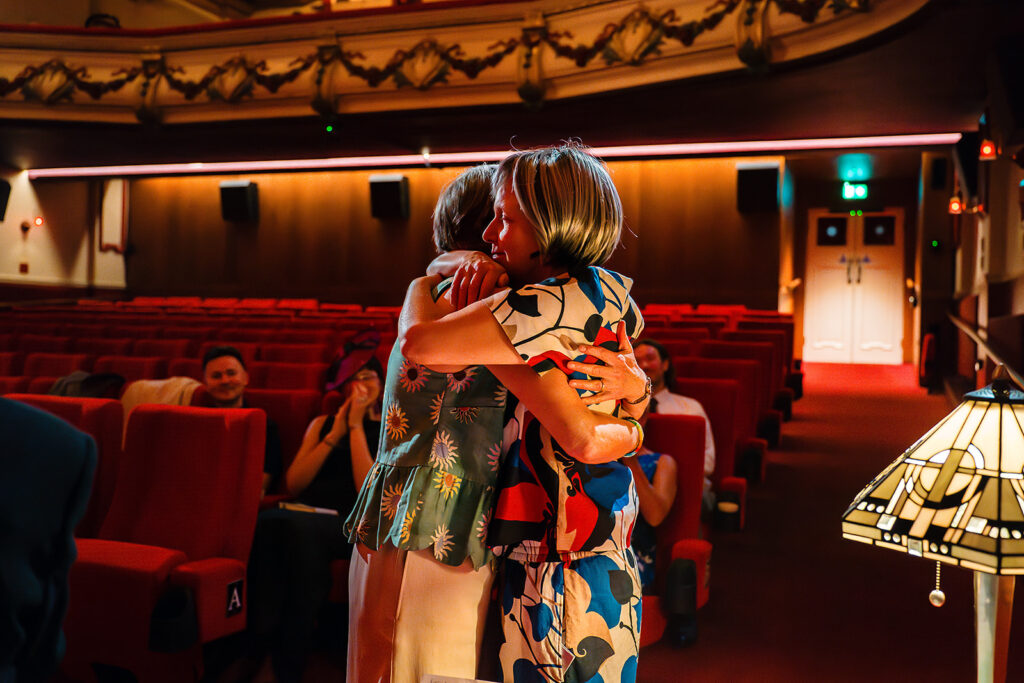 Beverly and Jane hugging in the aisle of the auditorium after the ceremony