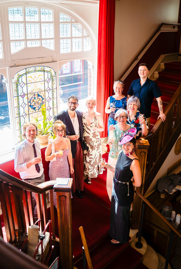 Beverly, Jane and their guests on the red-carpeted staircase of the Hyde Park Picture House, photographed from above