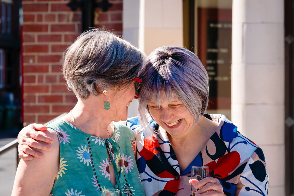 Beverly and Jane laughing with their heads together outside the Hyde Park Picture House