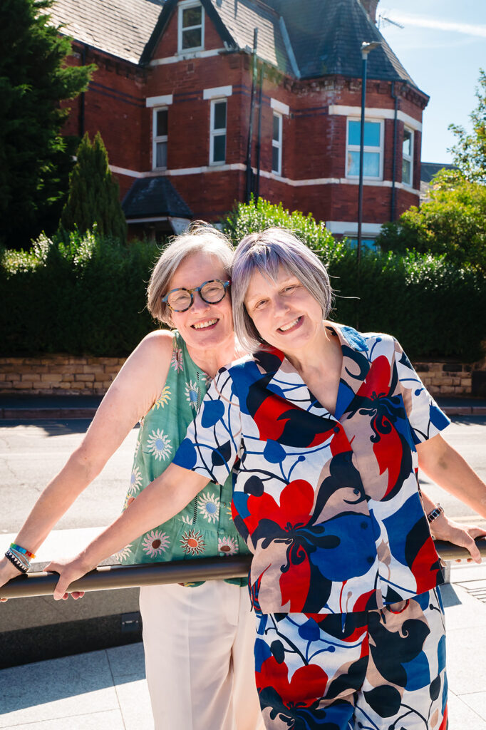 Beverly and Jane leaning on a railing in the sunshine outside the Hyde Park Picture House