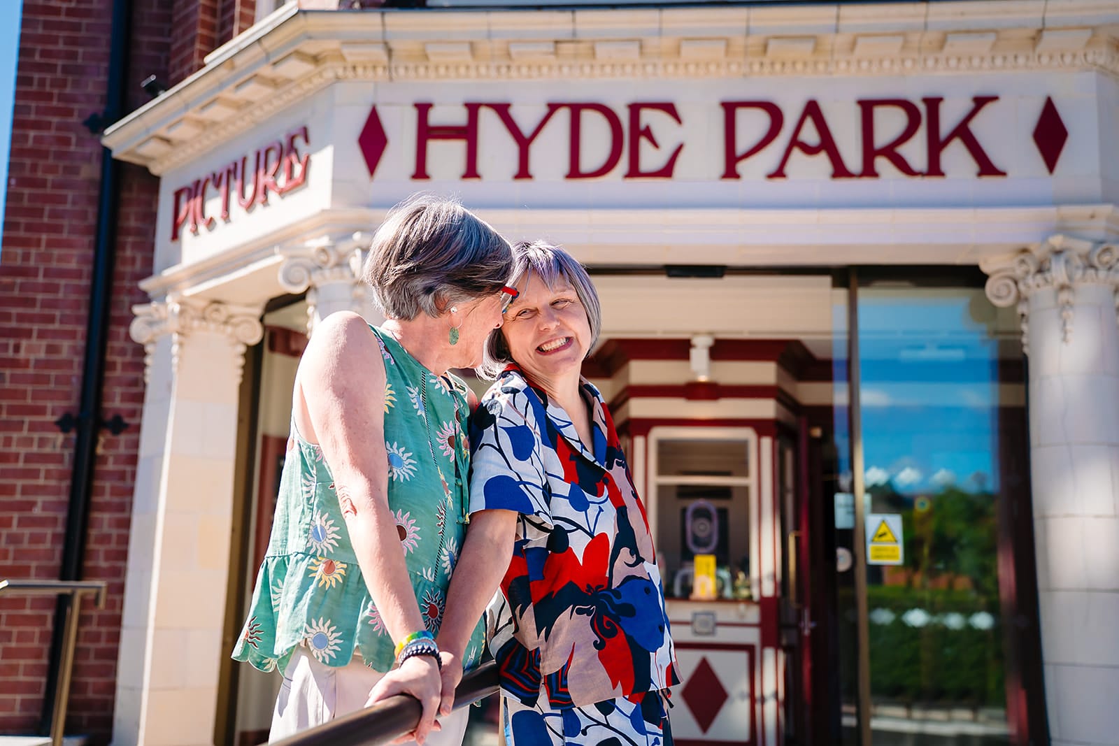 Beverly and Jane laughing together under the Hyde Park Picture House sign in Leeds