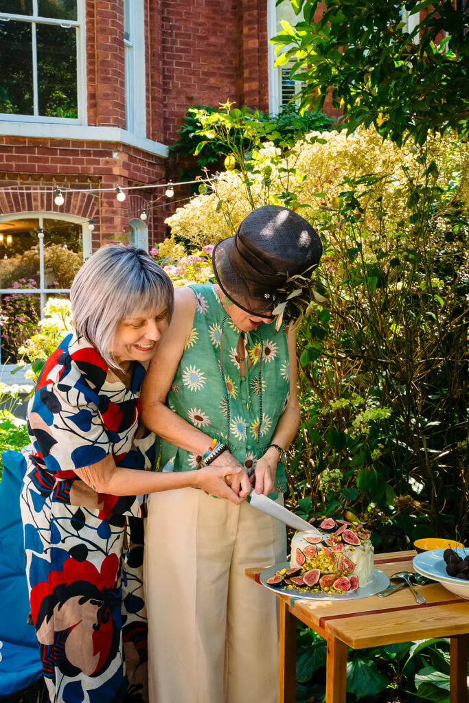 Beverly and Jane cutting their fig wedding cake together in the garden