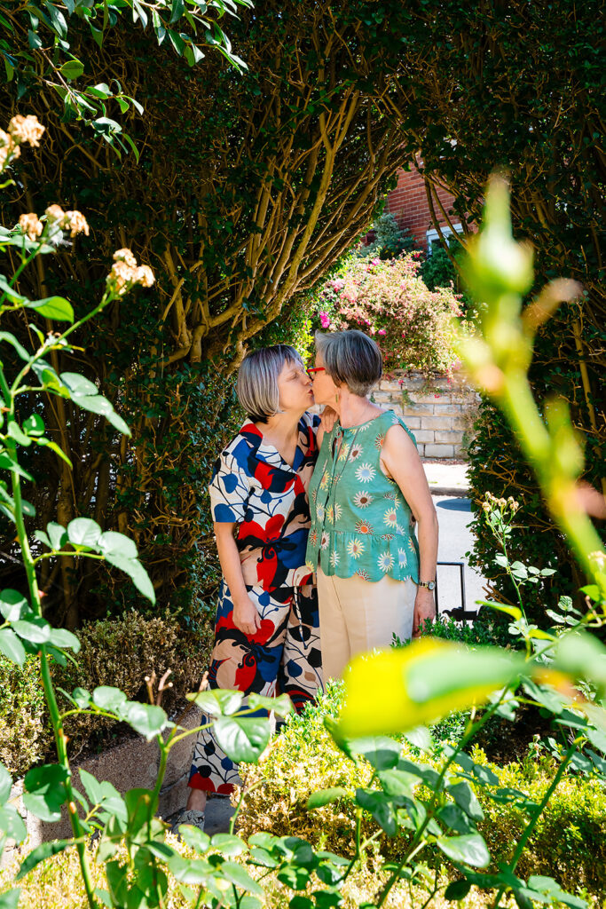 Beverly and Jane sharing a kiss among the roses at their garden wedding party in Leeds