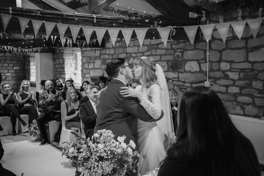 Black and white photo of Cody and Dale's first kiss as their guests clap
