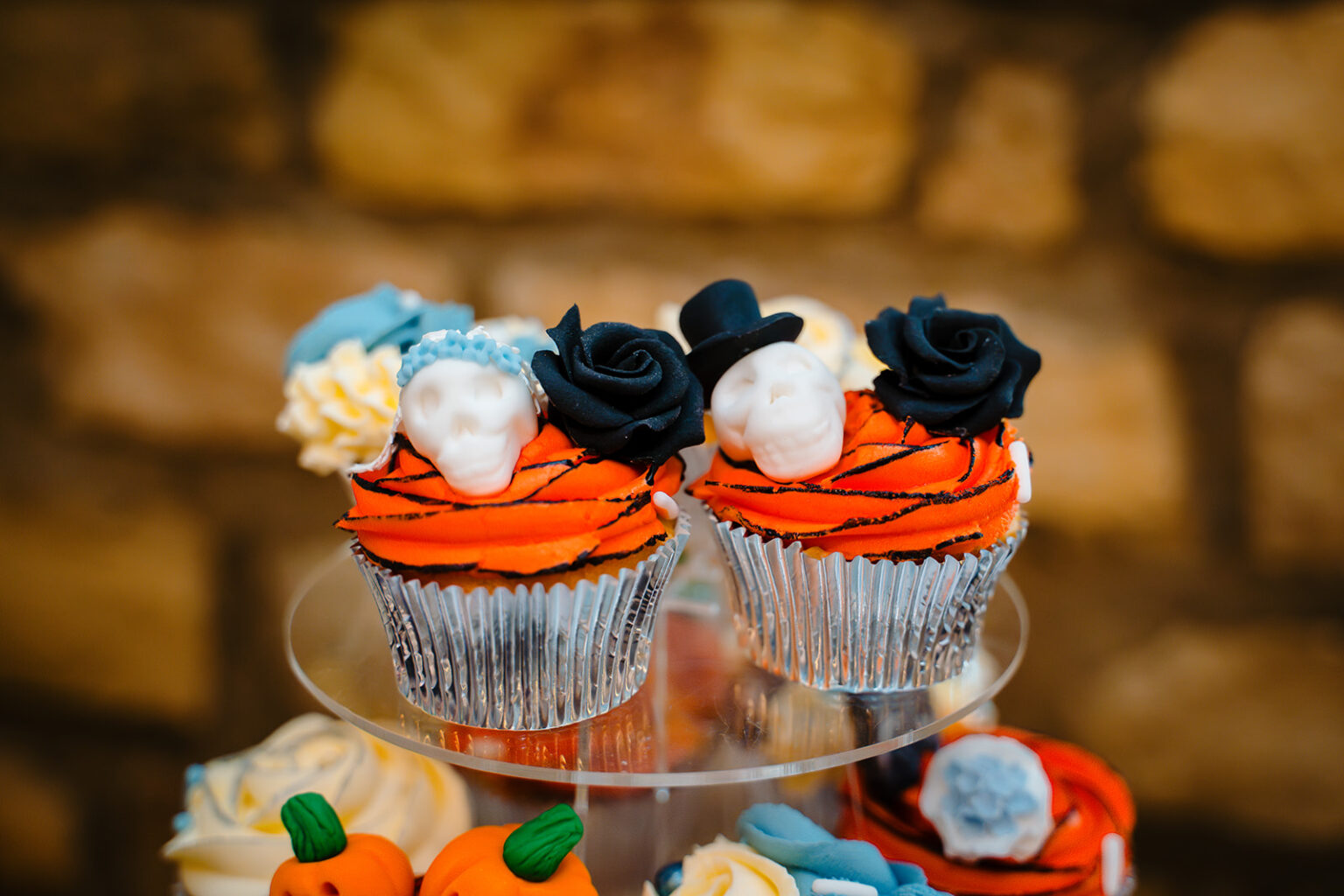 Orange cupcakes topped with white sugar skulls, black roses and top hats