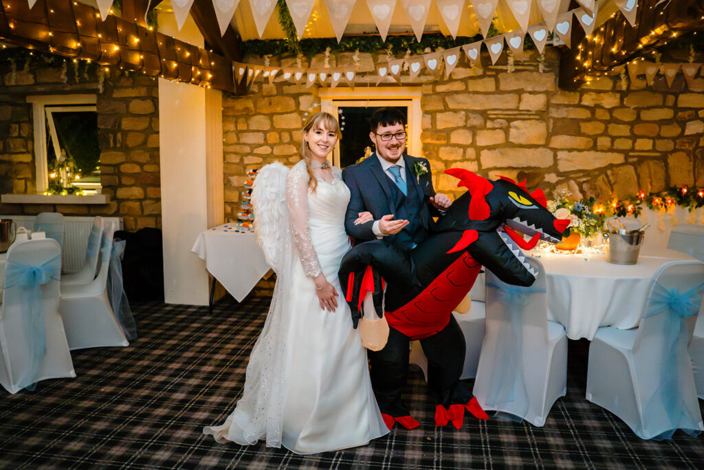Cody in angel wings beside Dale in an inflatable dragon costume at their Halloween wedding