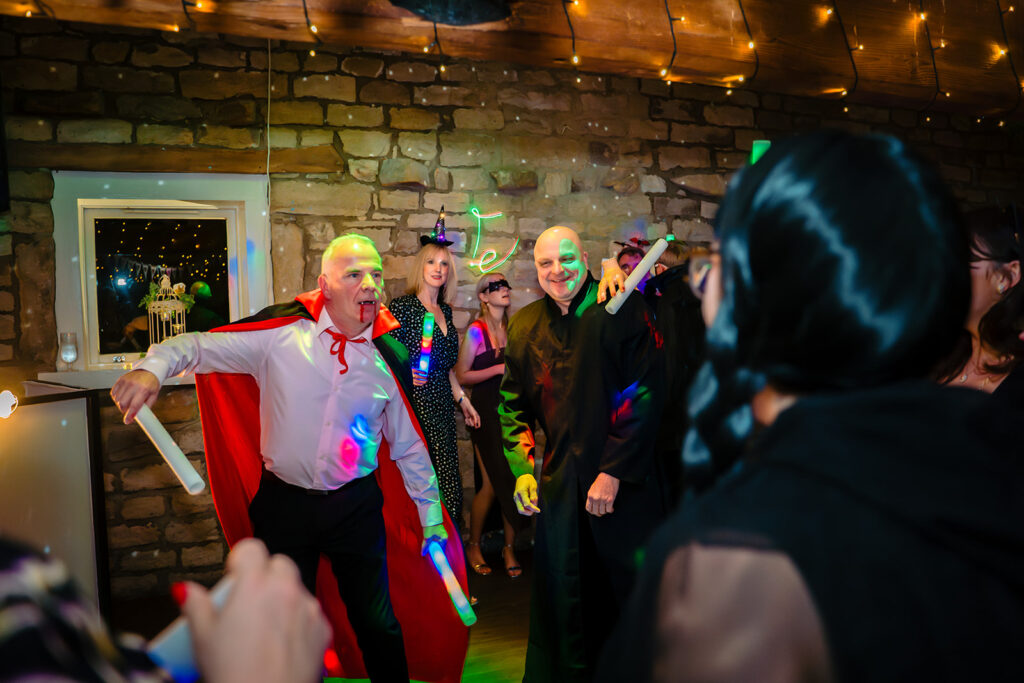 A guest dressed as Dracula dancing with glow sticks at Cody and Dale's Halloween wedding
