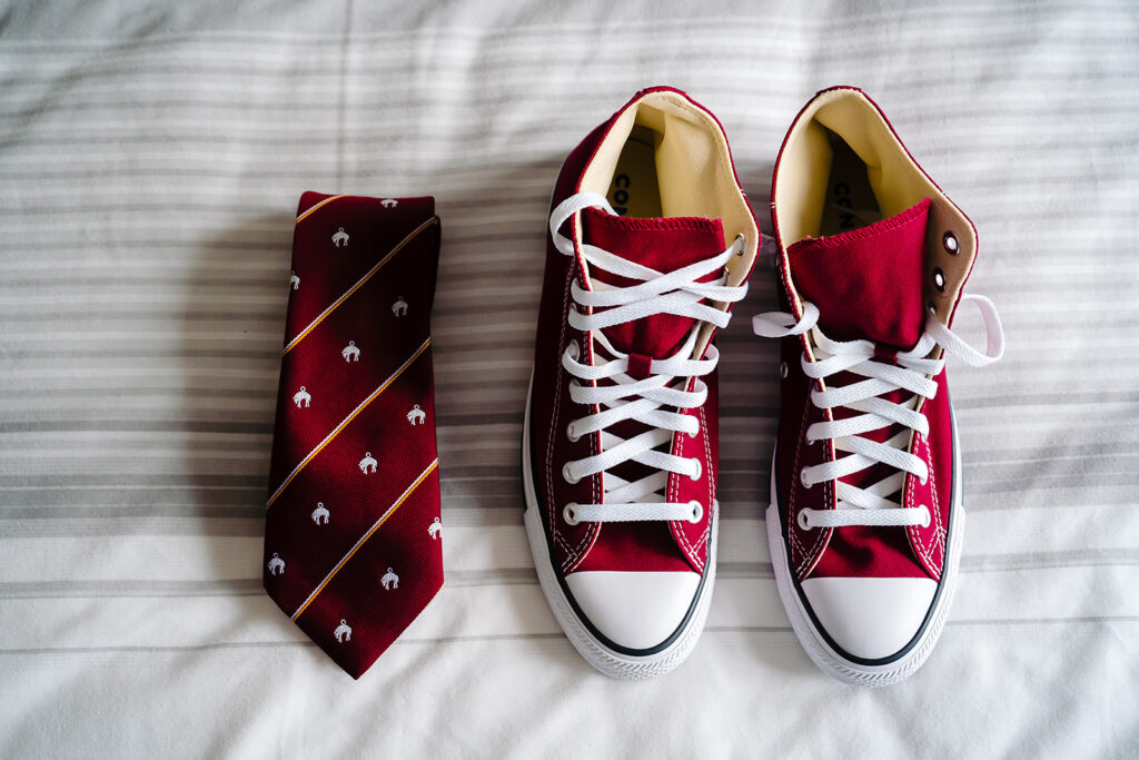 Red high-top canvas shoes with white laces and matching burgundy tie