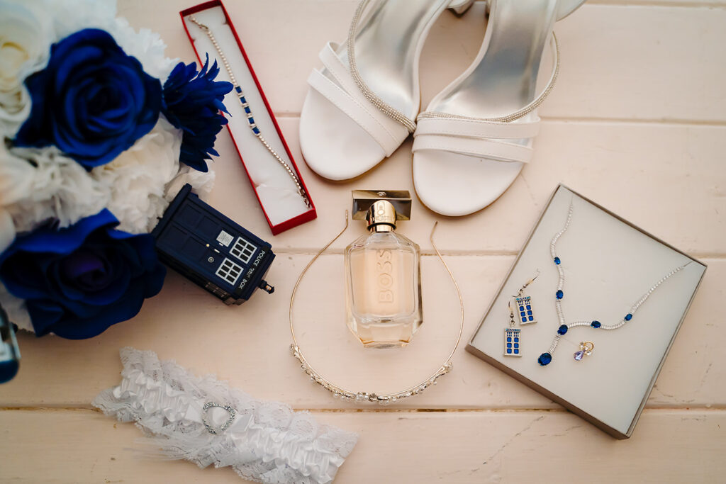 Wedding accessories: white shoes, blue flowers, jewellery, perfume