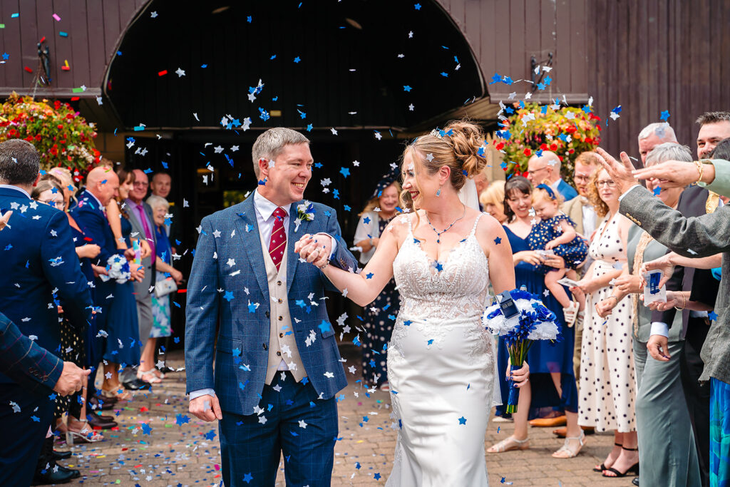 Bride and groom walking through blue and white confetti celebration