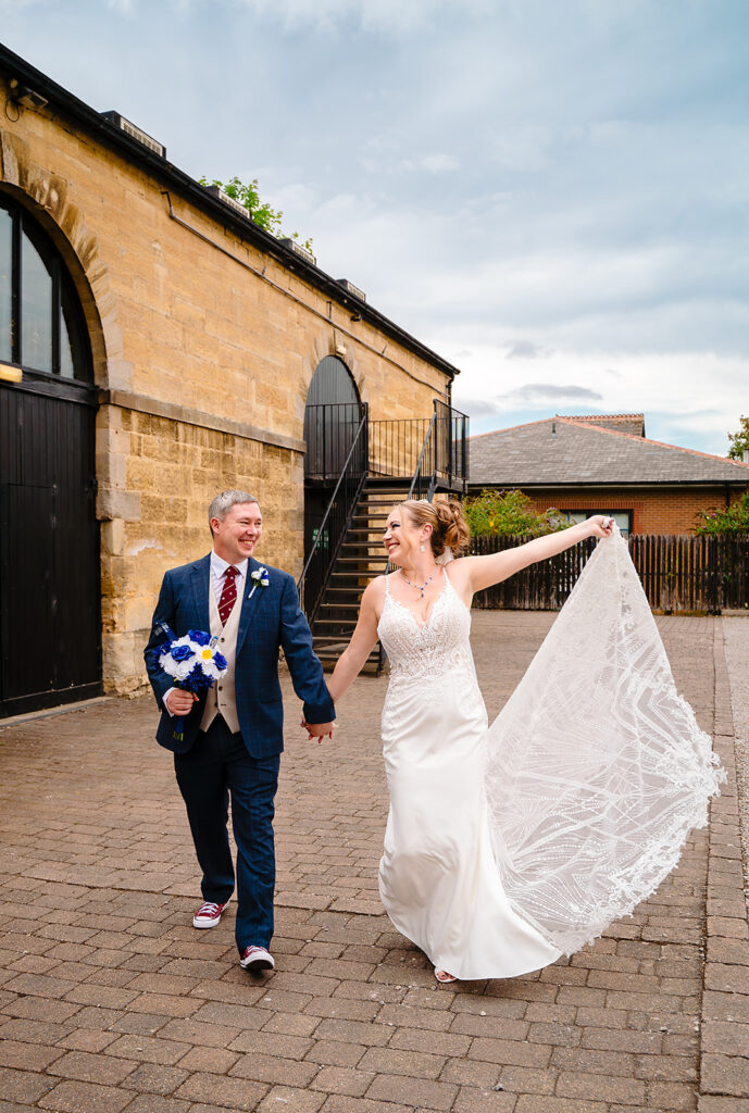 Bride and groom walking outside historic stone building