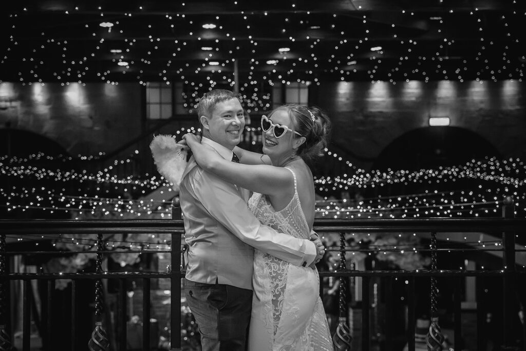 Couple embracing on balcony with festive bokeh lights background