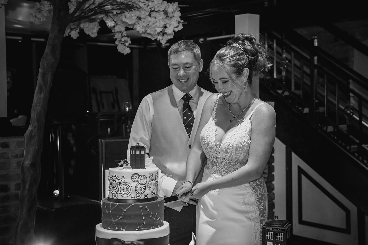 Bride and groom cutting themed wedding cake together