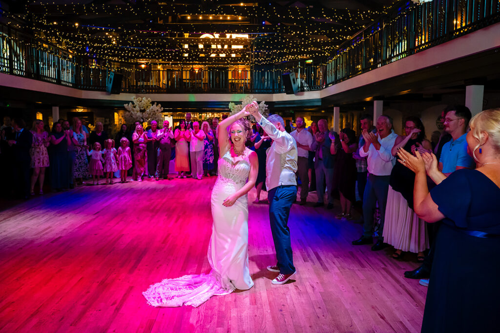 Bride and groom dancing at wedding reception with guests
