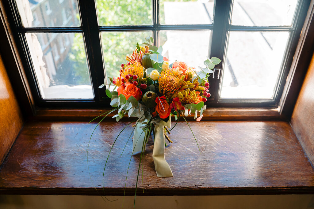 Autumn wedding bouquet of orange roses and pincushion proteas on a window sill at the Grand Hotel, York