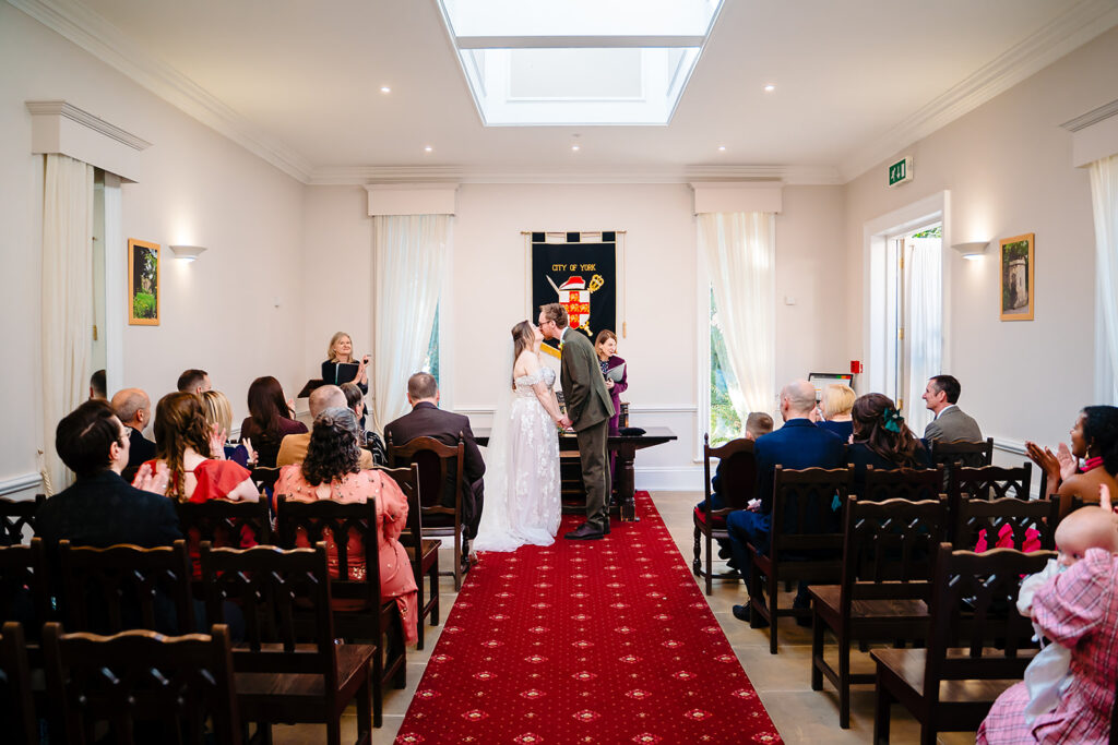 Ellissa and Anthony's first kiss at the end of the red aisle in York Register Office, Bootham
