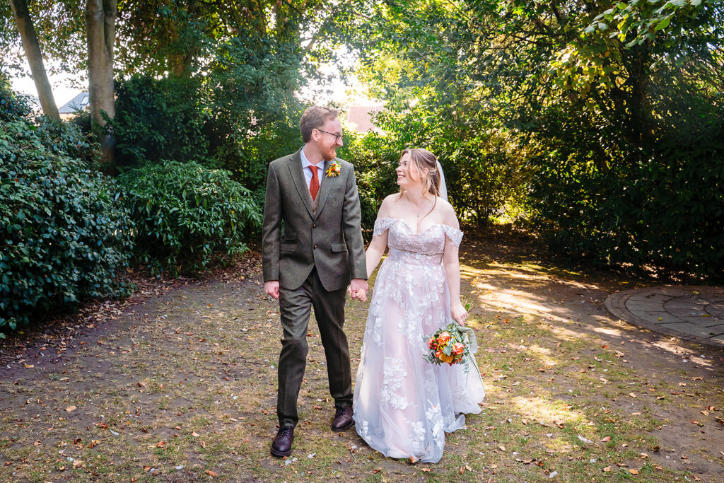 Ellissa and Anthony walking hand in hand along a tree-lined path in York