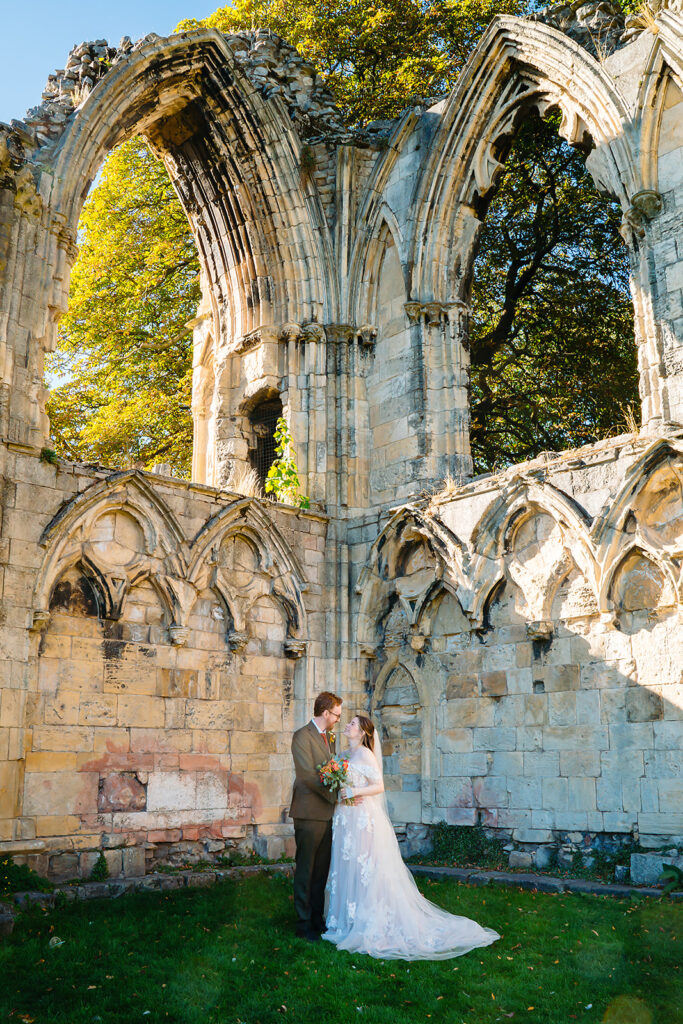 Ellissa and Anthony kissing beneath the ruined arches of St Mary's Abbey in Museum Gardens, York
