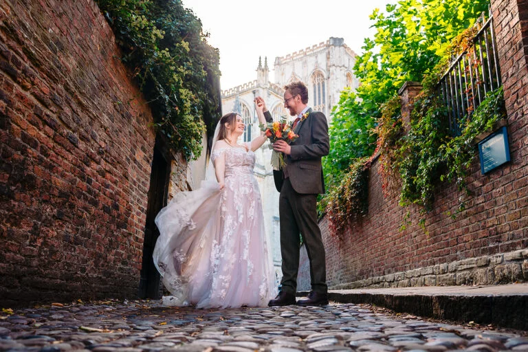 Anthony twirling Ellissa on a cobbled lane with York Minster rising behind them