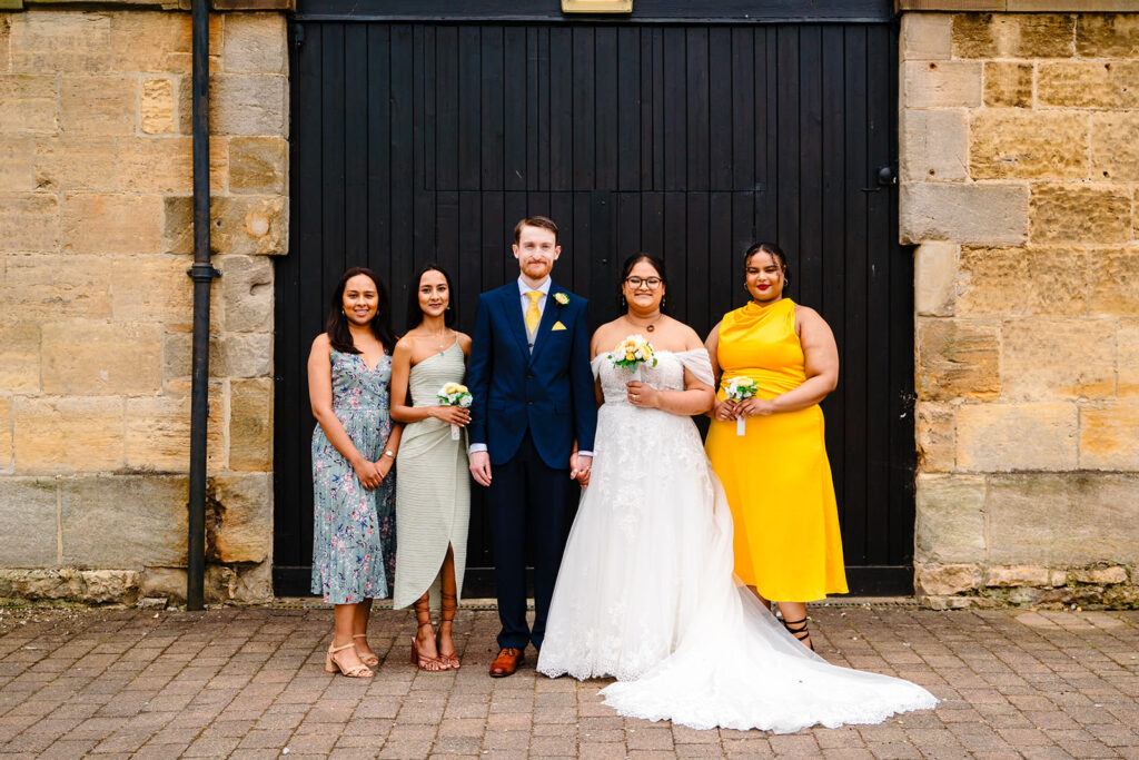 Fran and Andy with their bridesmaids in front of the black arched doors at the side of the Engine Shed