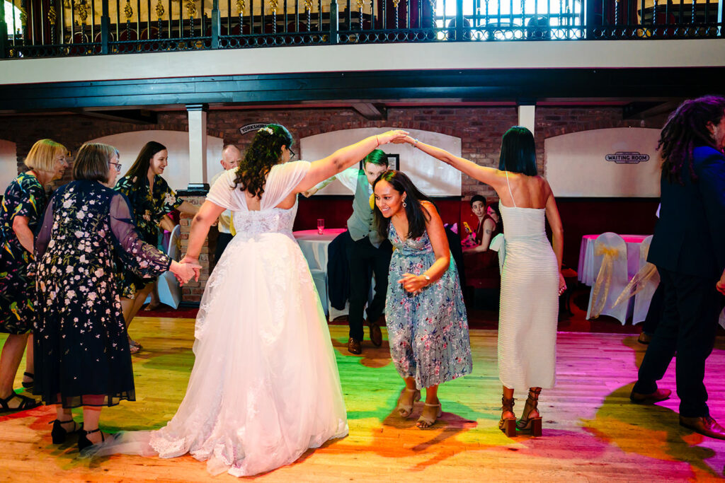Fran ducking under an arch of guests' arms during a ceilidh dance at the Engine Shed
