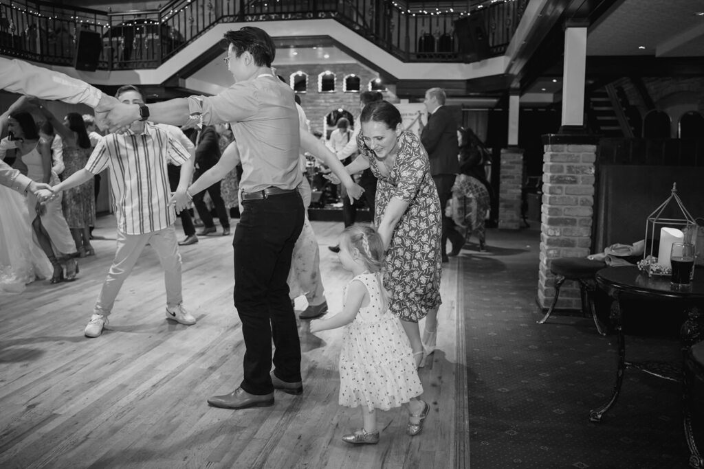 A little girl and adults dancing in a ceilidh circle at Fran and Andy's wedding