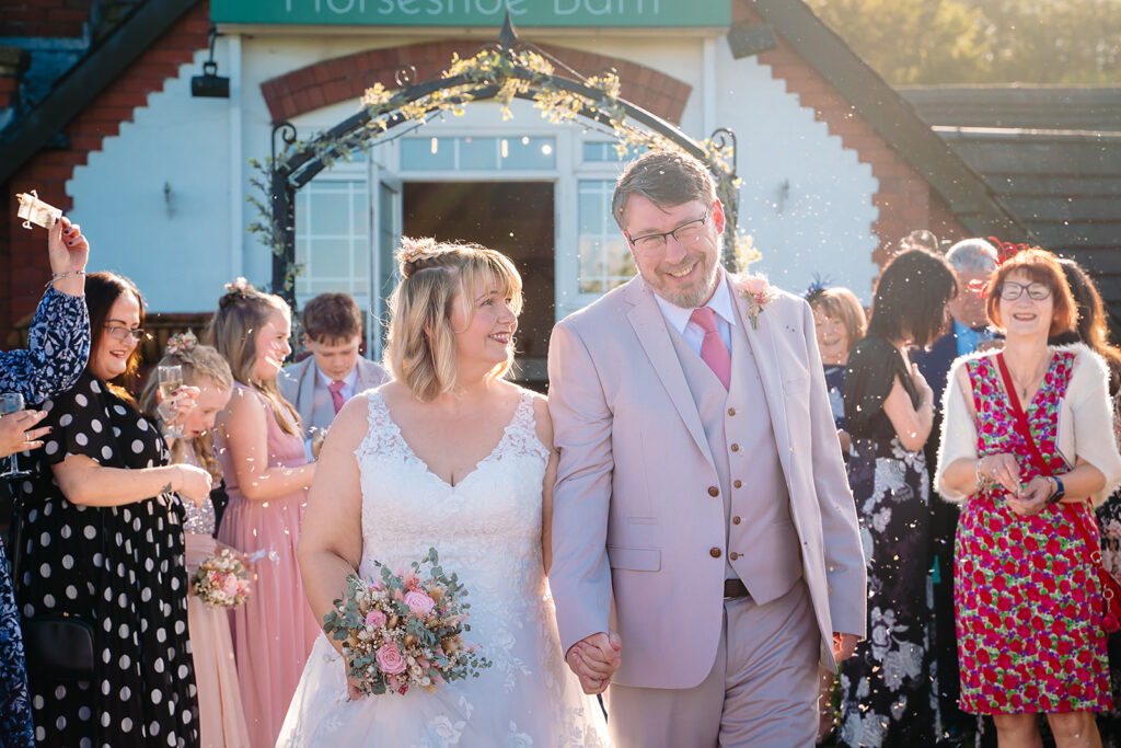 Guests throwing confetti over Kay and Steven outside the Horseshoe Barn