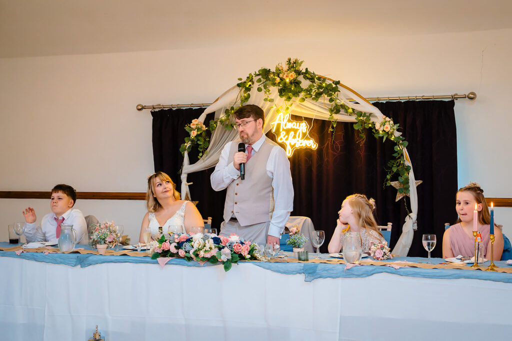 Steven giving his speech at the top table as Kay and the kids listen