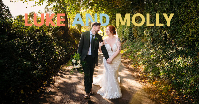 Couple walking on tree-lined path, wedding attire.