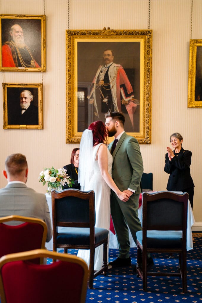 Bride and groom kissing during wedding ceremony inside the West Room at Leeds Civic Hall.