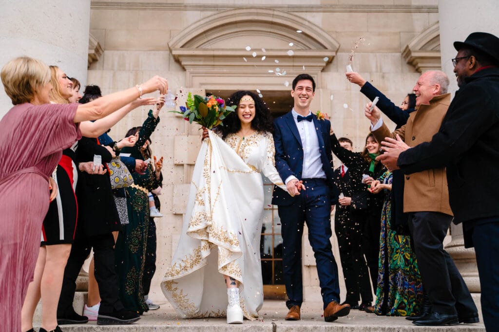 Bride and groom exiting wedding ceremony at Leeds Civic Hall joyfully.