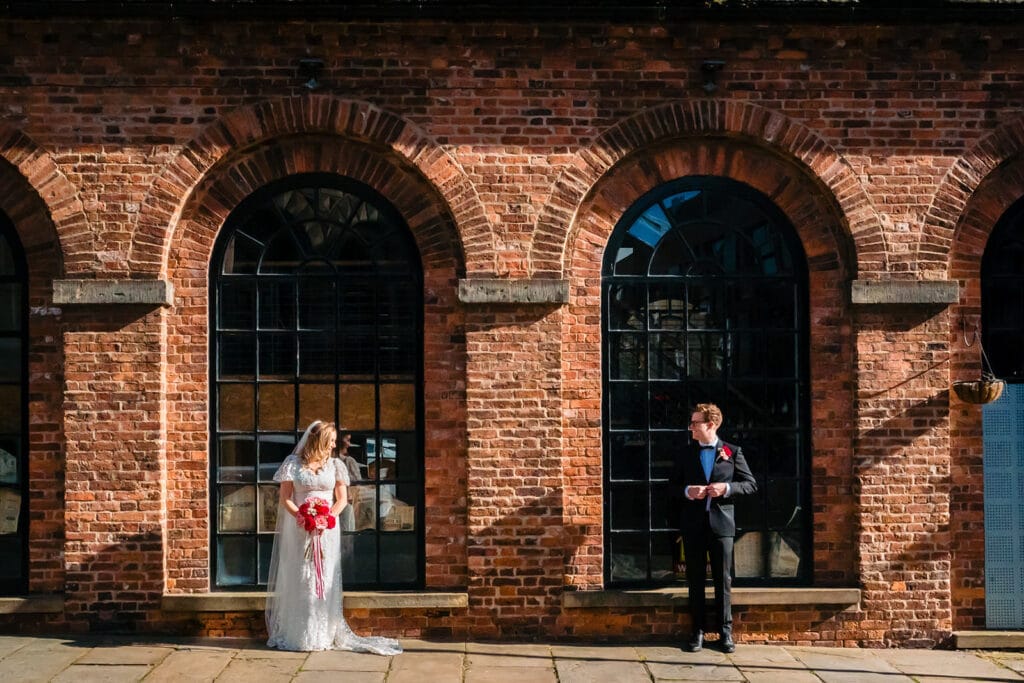 Wedding couple outside brick building with arches.