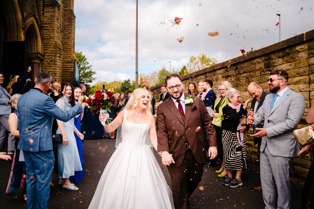 Rebecca and Nicholas walking through confetti outside Dewsbury Baptist Church