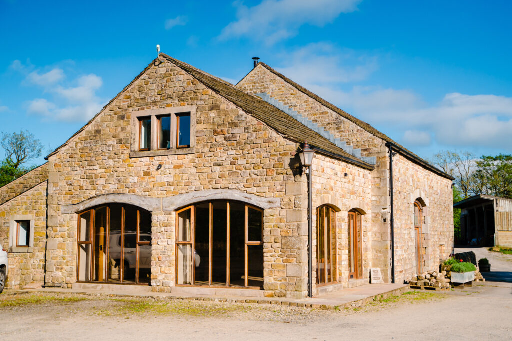 Stone barn with wooden doors under blue sky at The Out Barn.