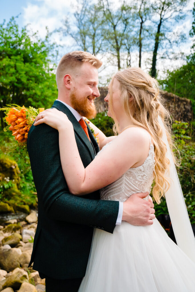 Bride and groom embracing outdoors, smiling