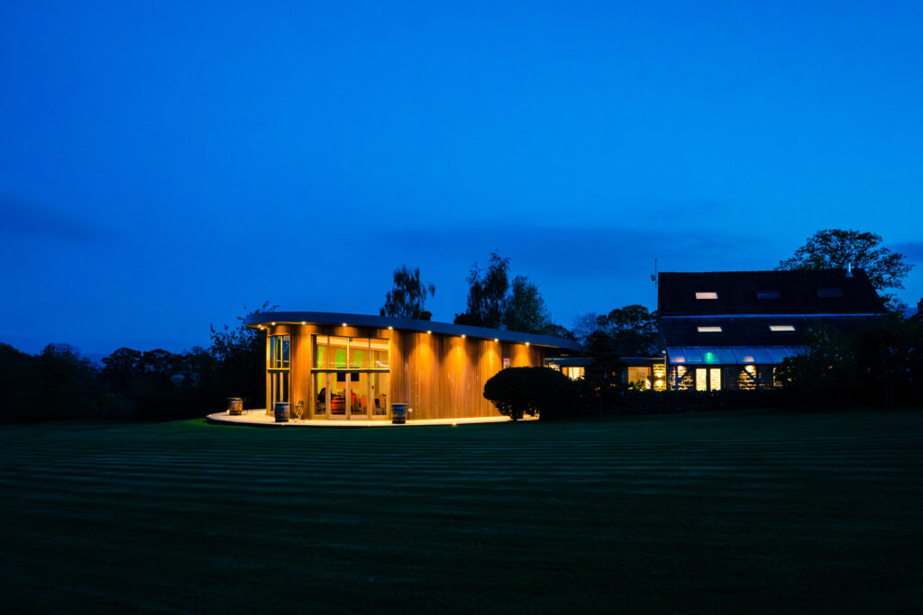 The Out Barn illuminated at night in rural setting